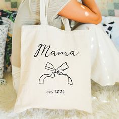 This stylish, whimsical tote says "Mama" in a chic black color with a matching bow and a spot for the birth date of her baby. The perfect trendy keepsake that any mother of a baby boy or baby girl will treasure. White Rectangular Diaper Bag Gift, Rectangular White Diaper Bag Gift, Rectangular White Diaper Bag As Gift, Cute Personalized Black Bag, Personalized Bags For Mother's Day, Personalized Cute Bag For Gift, Cute Personalized Bag As Gift, Coquette Black, Black Bow