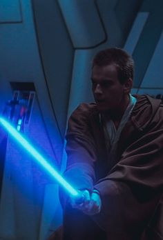 a man in a star wars costume holding a blue light saber with his right hand