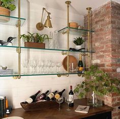 the shelves are filled with wine glasses, bottles and other items in front of a brick wall