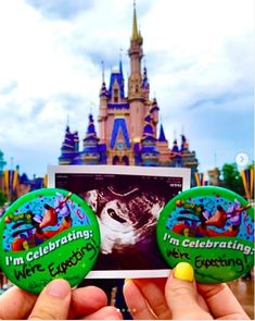 two people holding up small magnets in front of a castle