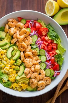 a salad with shrimp, avocado, corn and tomatoes in a white bowl