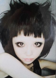 a woman with black hair and big eyes posing for the camera