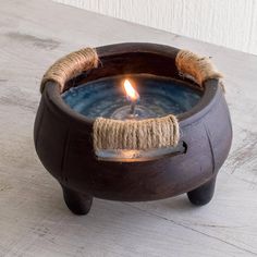 a candle that is sitting in a bowl on a table with rope wrapped around it