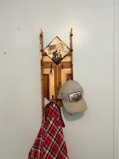 a hat is hanging on the wall next to a wooden sleigh with a baseball cap