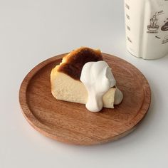 a piece of cheesecake on a wooden plate next to a cup of coffee and milk