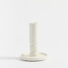 a small white candle holder on a white surface with no one in the room around it