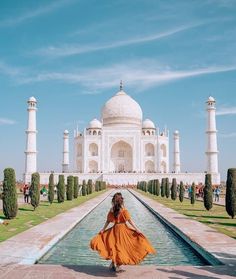 a woman in an orange dress is standing near the tajwa mosque, india