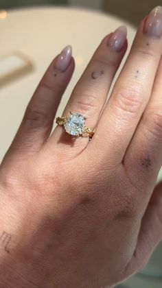 a woman's hand with a diamond ring on top of her left hand,