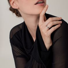 a woman in black shirt holding her hand to her chin and looking off into the distance