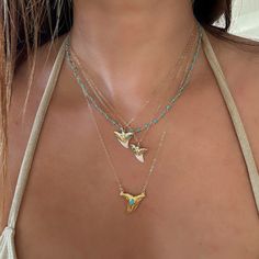 Turquoise Shark Tooth Necklaces. We know you will want to swim in the ocean with your shark tooth necklace so we used waterproof vermeil gold for this piece, and we always use authentic stones, so our turquoise is 100% real Arizona turquoise.The shark teeth we use are found on the shores of Florida and are all a bit different in size and shape. You will receive one shark tooth necklace. Gold with turquoise and white tip. Some photos show other pieces as layering options and styling inspiration. Cheap Beach Pendant Jewelry, Cheap Ocean-inspired Jewelry For Women, Leah Fish Jewelry, Layers Necklaces Gold, Dainty Shark Tooth Necklace Real Gold, Dainty Shark Tooth Necklace Smile The Ocean, Outerbanks Inspired Jewelry, Whale Shark Necklace, Gold Turquoise Jewelry