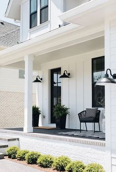 a white house with two black chairs on the front porch