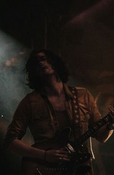 a man with long hair playing an electric guitar