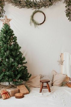 a small christmas tree sitting on top of a bed next to a wooden step stool