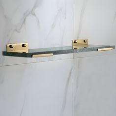 two brass handles on the back of a marbled wall with white and grey walls