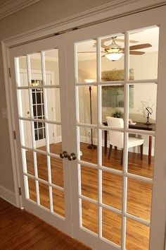 an empty living room with french doors and hard wood flooring