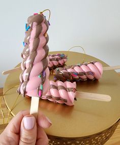 a hand holding a toothpick with chocolate and sprinkles on it