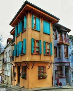 an old building with blue shutters on the windows and balconies in front