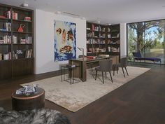 a living room filled with lots of furniture and bookshelves on top of a hard wood floor