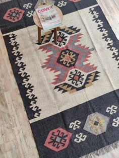 an old rug is on the floor with a chair next to it and a magazine