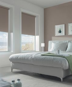 a white bed sitting in a bedroom next to two windows with blinds on each side