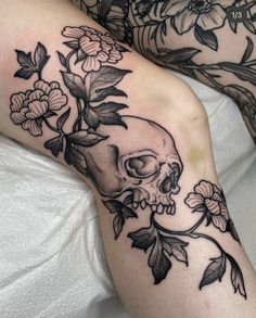 a skull and flowers tattoo on the leg