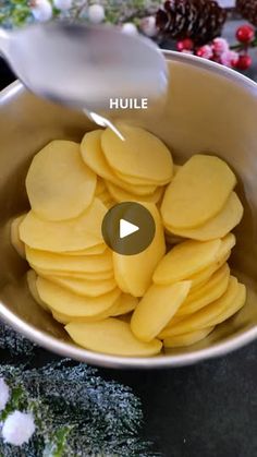 a bowl filled with cut up potatoes on top of a counter next to pine cones