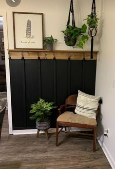 a room with a chair, potted plants and a wall hanging on the wall