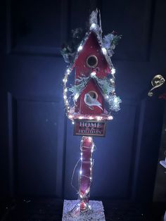 a red birdhouse with christmas lights on it