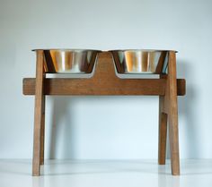 two metal bowls sitting on top of a wooden stand