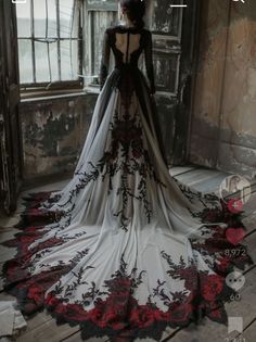 the back of a woman's wedding dress in front of an open window with red roses on it