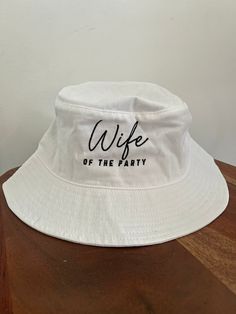 a white bucket hat with the words wife of the party printed in black on it