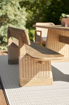 a wooden bench sitting on top of a patio next to a table with chairs and potted plants