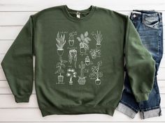 Add a touch of greenery to your wardrobe with our stylish houseplant sweatshirt. Made from soft, high-quality material, this sweatshirt is comfortable to wear and perfect for any plant lover. Featuring a vibrant and detailed design of various houseplants, this sweatshirt is sure to turn heads. Perfect for casual wear or as a gift for the plant enthusiast in your life. Get yours today and show off your love for all things green! Plant Sweatshirt, Plant Lady Shirt, Plant Mom Sweatshirt, Gardening Casual Long Sleeve T-shirt With Plant Print, Casual Long Sleeve Tops With Plant Print, Casual Green Tops With Plant Print, Spring Relaxed Fit T-shirt With Plant Details, Green Tops With Plant Print For Fall, Casual Fall Tops With Plant Print, Spring Green Tops With Plant Details, Green Spring Sweatshirt For Everyday Wear, Botanical Relaxed Fit Tops With Plant Print