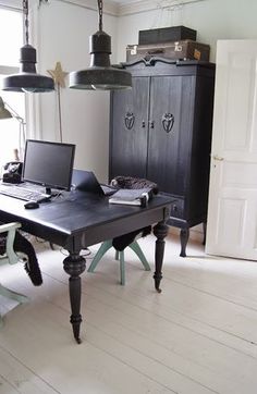 a desk with two laptops on it in front of an armoire and hanging lights