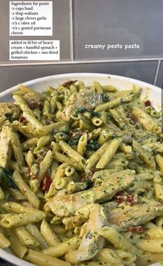 pasta with pesto and chicken in a white bowl on top of a tiled counter