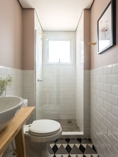 a white toilet sitting next to a sink in a bathroom under a window on top of a tiled floor