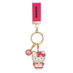 a hello kitty keychain with a pink ribbon around it's neck and an emblem on the front