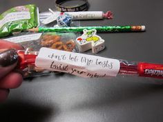 a hand holding a candy bar with writing on it next to some other candies