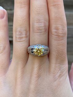 a woman's hand with a yellow and white diamond ring on top of it