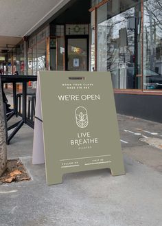 an open sign on the sidewalk in front of a building that says we're open live breathe