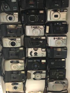 a bunch of cameras are stacked on top of each other in a room with white walls