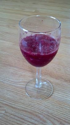 a glass filled with liquid sitting on top of a wooden table