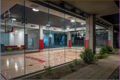 an indoor basketball court is reflected in the glass wall of this building's lobby