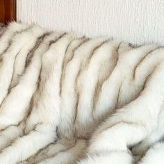 a white and grey fur blanket sitting on top of a bed