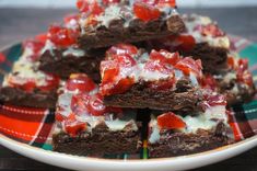 chocolate brownies with strawberry toppings on a plaid tablecloth covered plate, ready to be eaten