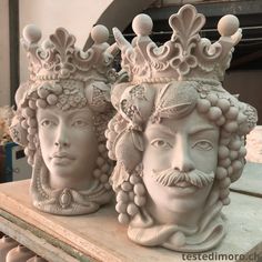 two statues of men wearing crowns on top of a table