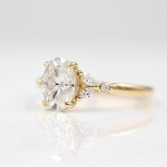 a yellow gold engagement ring with an oval cut diamond and three small diamonds on the side