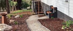 a wooden bench sitting on the side of a house next to a garden and stairs