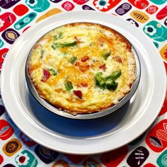 an omelet is sitting on a white plate with colorful designs around the edges