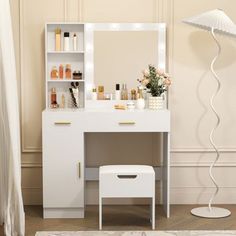 a white vanity table with a mirror and stool next to a floor lamp in a room